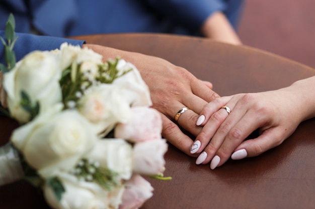 Just married couple.  Hand in hand of newlyweds with wedding rings and wedding bouquet.