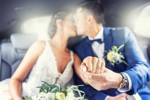 Just married couple kisses in the car showing rings on fingers towards the camera