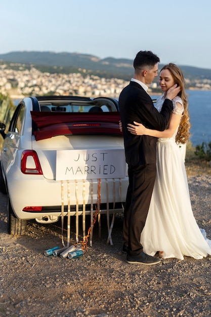 Just married couple next to little car