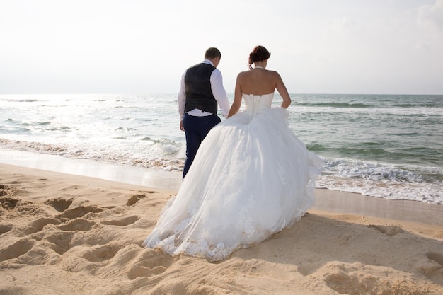 Just-married couple standing by the ocean