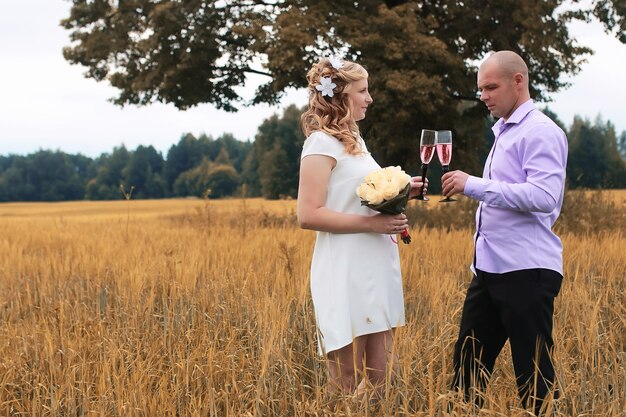 Just married lovers walking in a field in autumn day