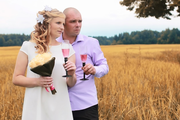 Just married lovers walking in a field in autumn day