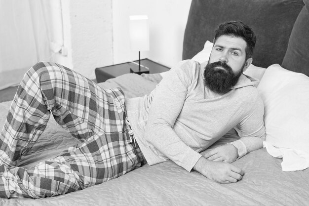 Just one more minute in bed energy and tiredness bearded man hipster want to sleep in morning brutal sleepy man in bedroom mature male with beard in pajama on bed asleep and awake comfort bed