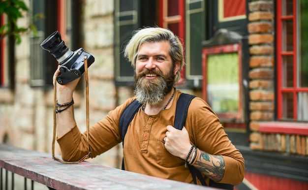 Just perfect photography in modern life travel tips\
professional photographer use vintage camera bearded man hipster\
take photo photo shooting outdoor brutal man traveler with retro\
camera