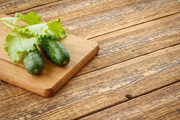 Cetrioli appena raccolti e insalata verde su tagliere e vecchie tavole di legno. verdure appena raccolte. vista dall'alto.