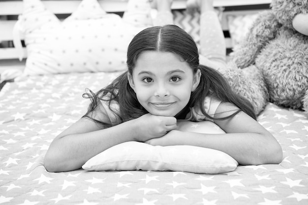 Just relaxing Girl child lay on pillow in her bedroom Kid prepare to go to bed Pleasant time stylish interior Girl kid long hair cute pajamas relaxing on pillow in bedroom Time to sleep or nap