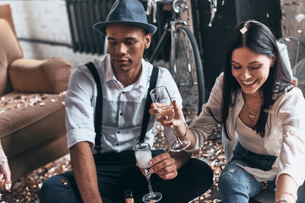 Just relaxing. Top view of modern young man drinking champagne while sitting on the floor with his friend