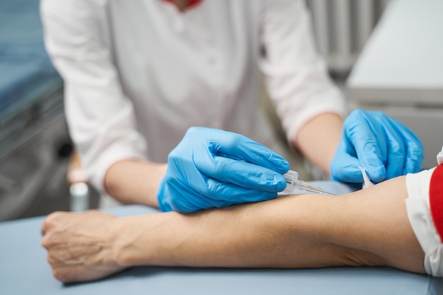 Just a second. Professional medical worker using sterile equipment while doing prick to her patient