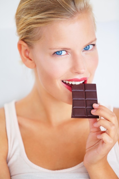 Just a small piece Smiling young woman enjoying a delicious piece of chocolate