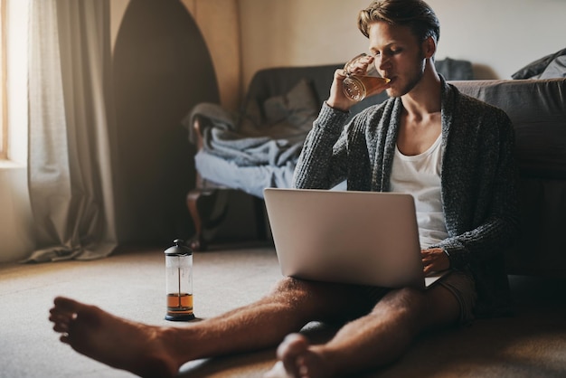 Just what I needed to start my day off Shot of a handsome young man using his laptop while sitting on the floor at home