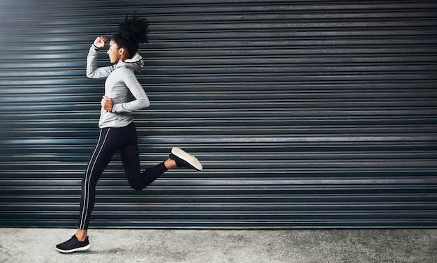 Foto fai del tuo meglio e dimentica il resto inquadratura di una giovane donna sportiva che corre su uno sfondo grigio