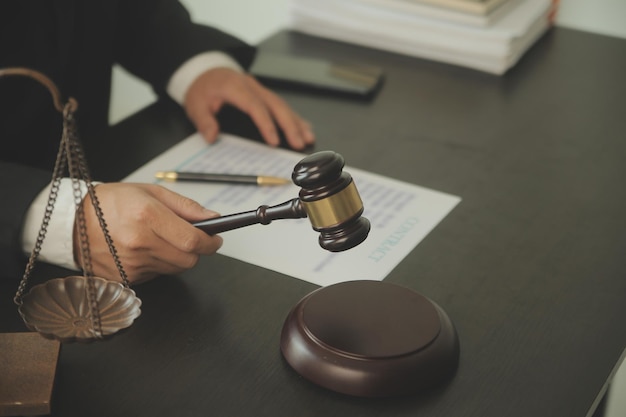 正義と法の概念法律顧問は、クライアントに小槌と法律との署名済みの契約を提示するか、バックグラウンドで法律事務所でチームミーティングを行う法律を持つ