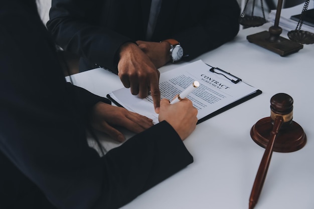 Justice and Law concept Legal counsel presents to the client a signed contract with gavel and legal law or legal having team meeting at law firm in background