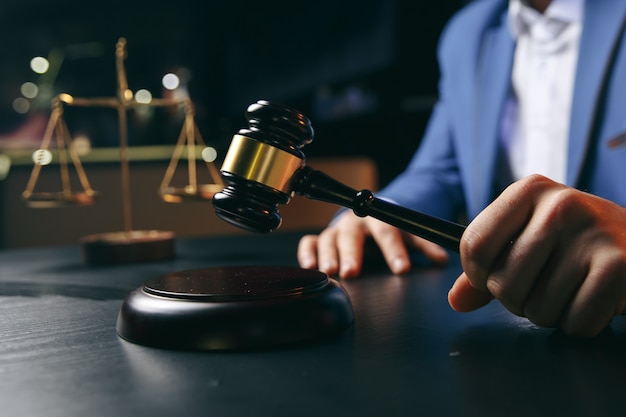 Justice and law concept.Male lawyer in the office with brass scale on wooden table,reflected view