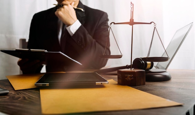 Концепция правосудия и праваСудья-мужчина в зале суда с молотком, работающим с компьютером и стыкующими клавиатурными очками на столе в утреннем свете