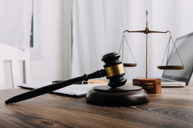 Justice and law conceptMale judge in a courtroom with the gavel working with computer and docking keyboard eyeglasses on table in morning light