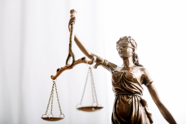 Justice and law conceptMale judge in a courtroom with the gavel working with computer and docking keyboard eyeglasses on table in morning light