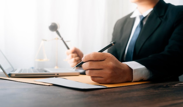 Justice and law conceptMale judge in a courtroom with the gavel working with computer and docking keyboard eyeglasses on table in morning light