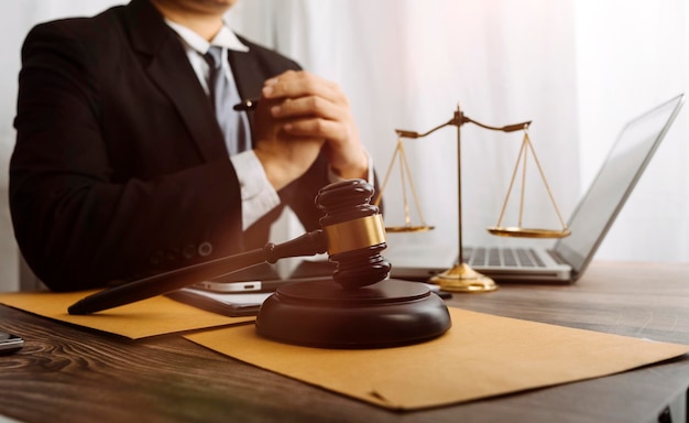 Justice and law conceptMale judge in a courtroom with the gavel working with computer and docking keyboard eyeglasses on table in morning light