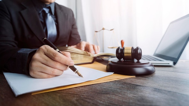 Justice and law conceptMale judge in a courtroom with the gavel working with computer and docking keyboard eyeglasses on table in morning light