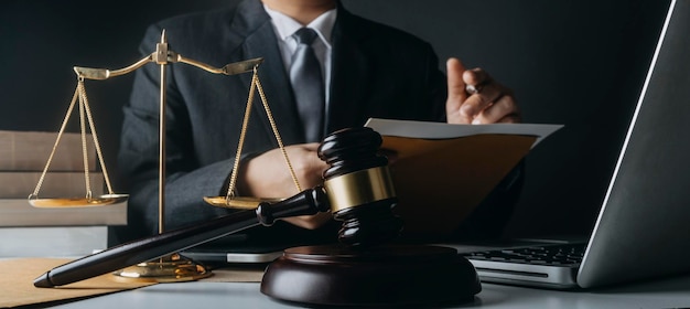 Justice and law conceptMale judge in a courtroom with the gavel working with computer and docking keyboard eyeglasses on table in morning light