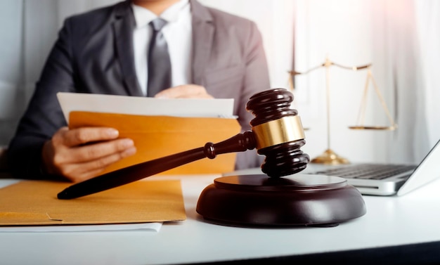 Justice and law conceptMale judge in a courtroom with the gavel working with computer and docking keyboard eyeglasses on table in morning light