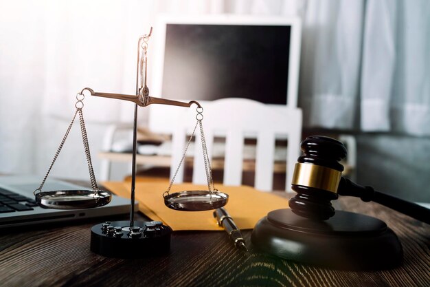 Justice and law conceptMale judge in a courtroom with the gavel working with computer and docking keyboard eyeglasses on table in morning light