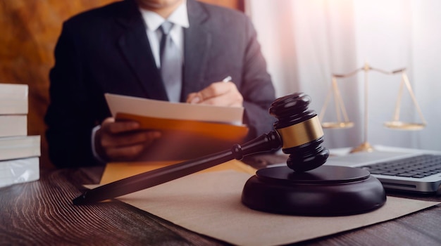 Justice and law conceptMale judge in a courtroom with the gavel working with computer and docking keyboard eyeglasses on table in morning light