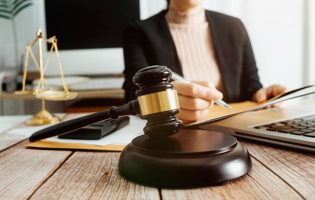 Justice and law conceptMale judge in a courtroom with the gavel working with computer and docking keyboard eyeglasses on table in morning light