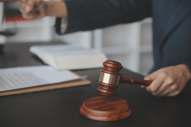 Justice and law conceptMale judge in a courtroom with the gavel working with computer and docking keyboard eyeglasses on table in morning light