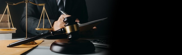 Justice and law conceptMale judge in a courtroom with the gavel working with computer and docking keyboard eyeglasses on table in morning light