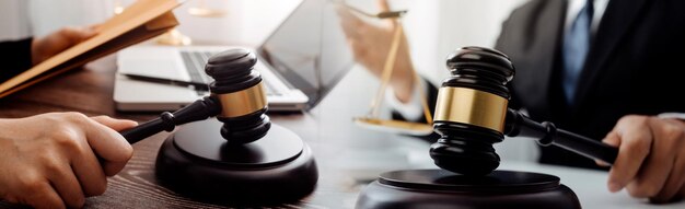 Justice and law conceptMale judge in a courtroom with the gavel working with computer and docking keyboard eyeglasses on table in morning light