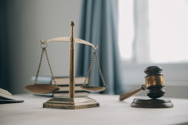 Justice and law conceptMale judge in a courtroom with the gavel working with computer and docking keyboard eyeglasses on table in morning light