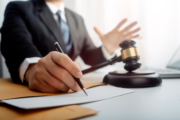 Justice and law conceptMale judge in a courtroom with the gavel working with computer and docking keyboard eyeglasses on table in morning light