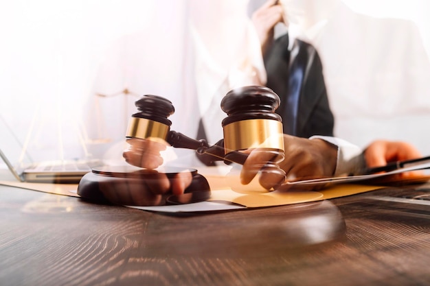 Justice and law conceptMale judge in a courtroom with the gavel working with computer and docking keyboard eyeglasses on table in morning light