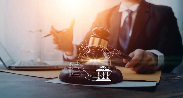 Justice and law conceptMale judge in a courtroom with the gavel working with computer and docking keyboard eyeglasses on table in morning light