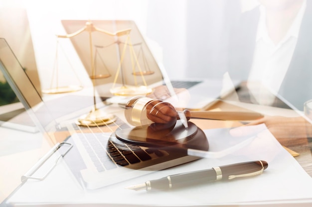 Justice and law conceptmale judge in a courtroom with the gavel working with computer and docking keyboard eyeglasses on table in morning light