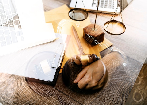 Justice and law conceptMale judge in a courtroom with the gavel working with computer and docking keyboard eyeglasses on table in morning light