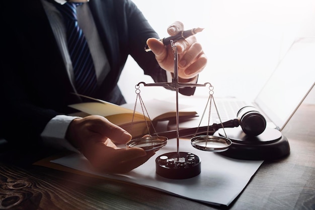 Justice and law conceptMale judge in a courtroom with the gavel working with computer and docking keyboard eyeglasses on table in morning light