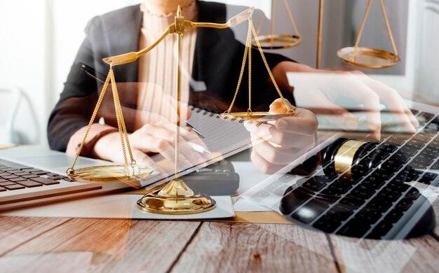 Justice and law conceptMale judge in a courtroom with the gavel working with computer and docking keyboard eyeglasses on table in morning light