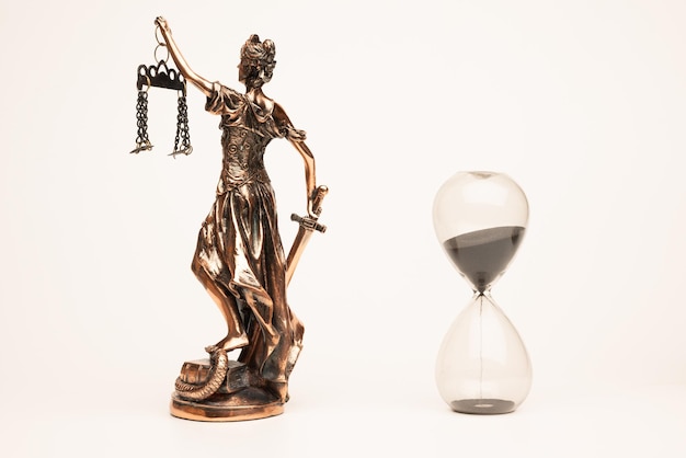 Justilia or Themis (Symbol of Justice) statue and hourglass isolated on white background with clipping path