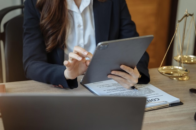 Justitie en recht concept Vrouw in kantoor de voorzittershamer werken met digitale tabletcomputer op houten tafel in zonlicht