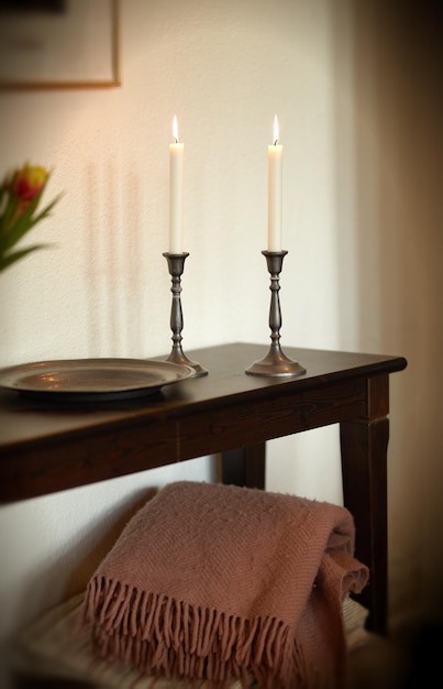 Kaars Elegante en decoratieve aangestoken kaarsen op een houten tafel thuis Geweven plaids en huisdecoraties voor een goede geur en om een kamer op te warmen Gezellige inrichting voor een modern appartement