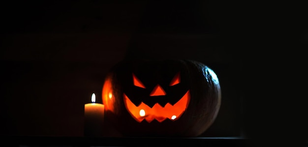 Kaars en griezelige lachende pompoen voor Halloween op zwarte achtergrond