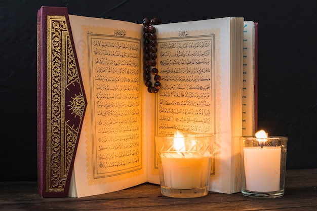 Kaarsen die pagina's van geopende koran aansteken