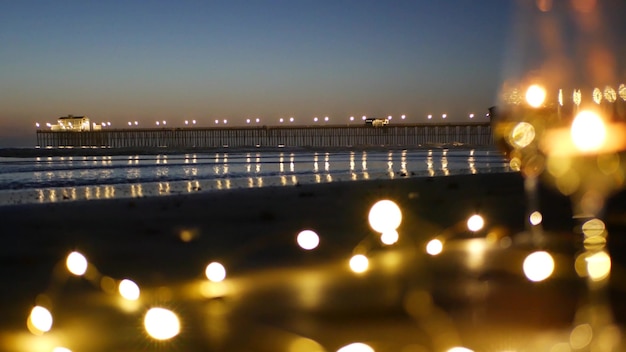 Kaarsvlammen in glas, romantische stranddatum door oceaangolven, zomerzee. Kaarslicht op zand.