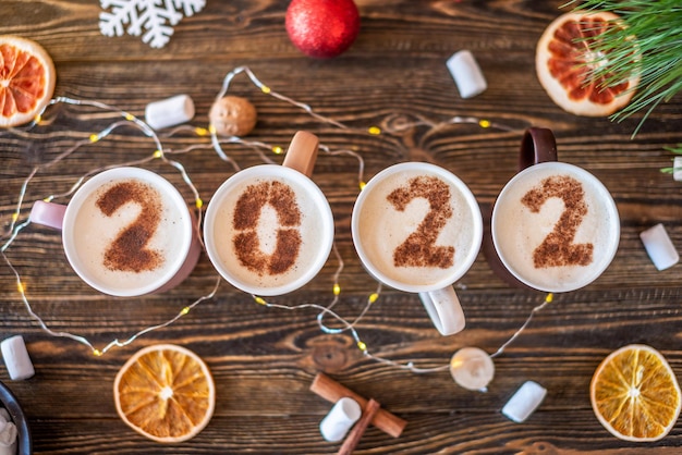 Kaart met nummers 2022 voor Nieuwjaar en Kerstmis. Kopje koffie met cijfers op houten achtergrond. Bovenaanzicht. plat leggen