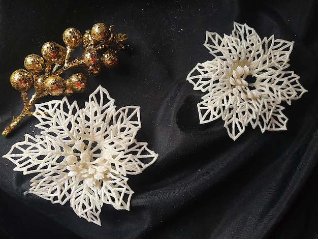 Kaart voor het nieuwe jaar en Kerstmis met versieringen Kerstversiering en schittert op een zwarte achtergrond Bruin glanzend gestreepte ballen bloemen en witte sneeuwvlokken gouden twijgen met bessen