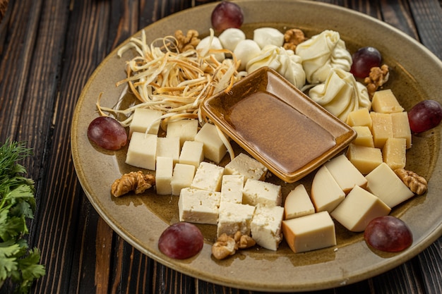 Kaas assortiment plaat op donkere houten achtergrond, vrije ruimte. bovenaanzicht op plaat met snack voor wijn met honing op ronde cateringschotel. hoge kwaliteit foto