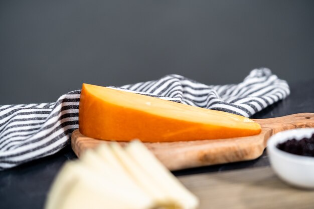 Kaas, crackers en fruit op een houten snijplank schikken om een kaasplankje te maken.